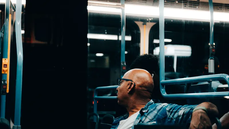 A man sitting on a bus at night, staring out the window.